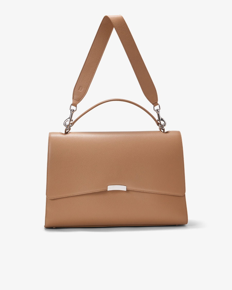 A structured tan leather handbag with a top handle, a detachable shoulder strap, and a silver-tone metal accent on the front flap, shown against a plain light gray background.