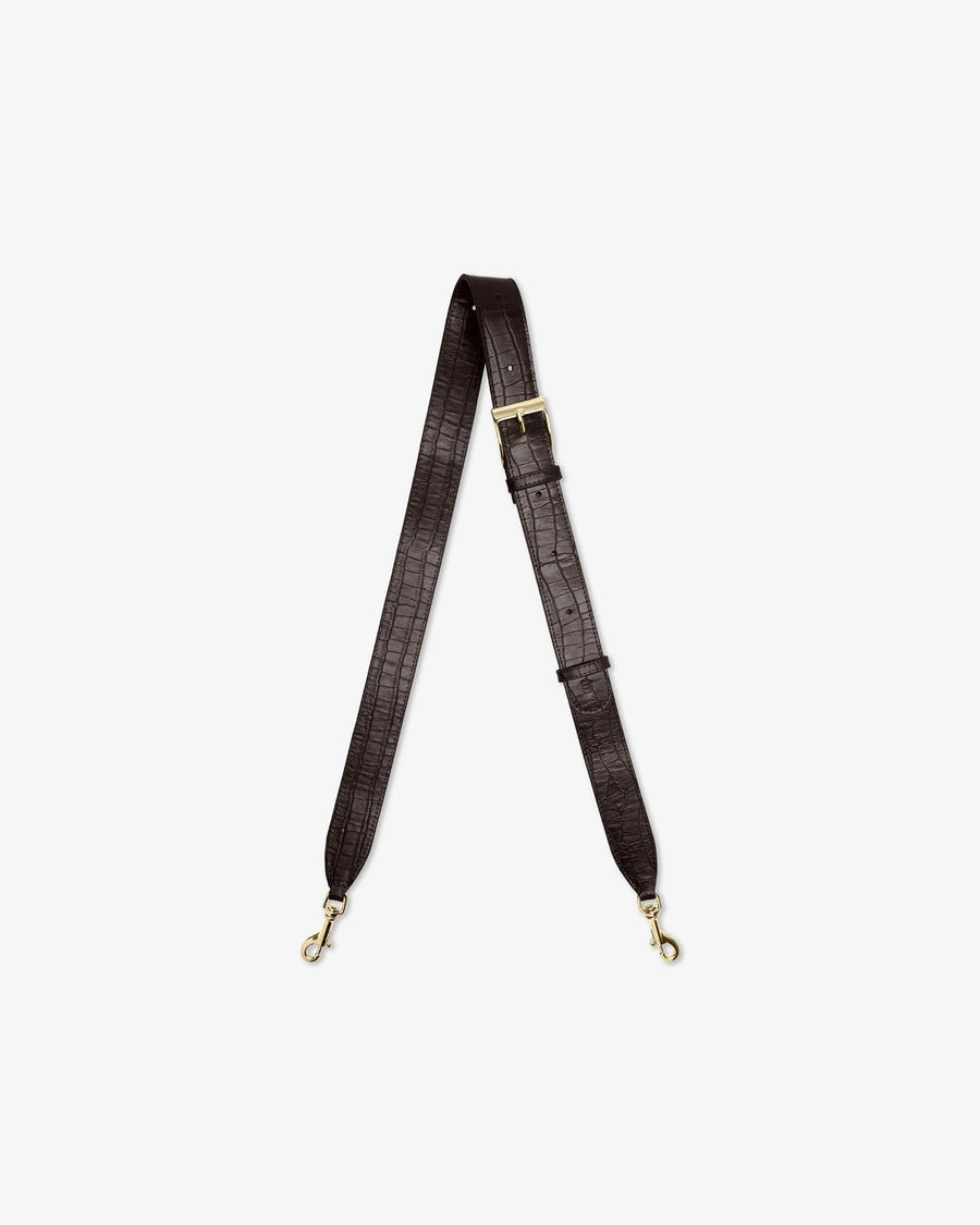 A dark brown crocodile-embossed shoulder strap with gold-tone hardware, displayed vertically against a light gray background.