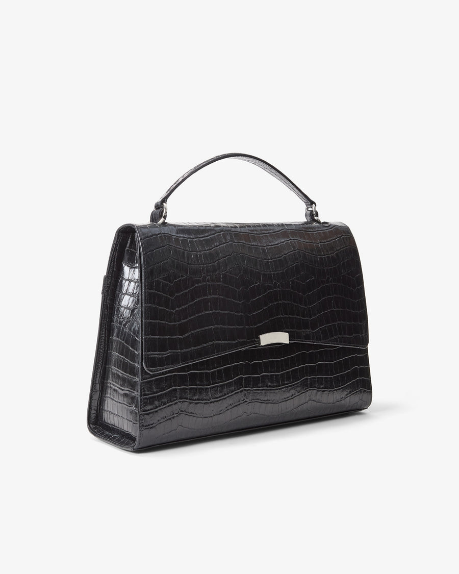 A black crocodile-embossed leather handbag with a top handle and a small silver metal accent on the front, shown against a plain white background.