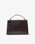A dark brown crocodile-embossed leather handbag with a top handle and a luggage strap, shown against a plain white background.