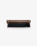 A brown leather bag shown open from the above, revealing a black interior lining and gold-tone hardware, set against a plain light gray background.