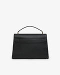 A black leather top-handle handbag with a structured rectangular silhouette and a luggage strap, photographed against a plain light gray background.