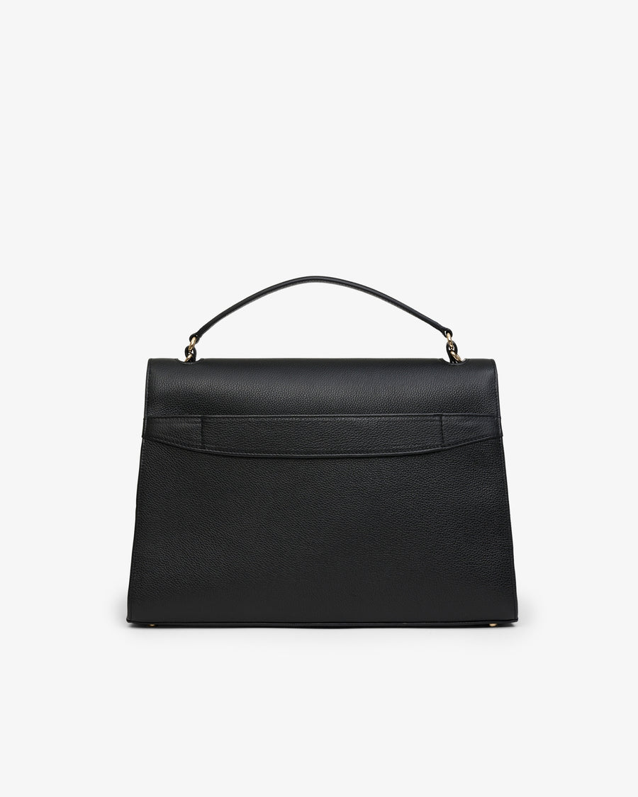 A black leather top-handle handbag with a structured rectangular silhouette and a luggage strap, photographed against a plain light gray background.