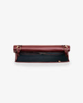 A burgundy leather bag shown from the top, open to reveal a black interior lining and gold-tone hardware, set against a plain light gray background.