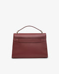 A structured burgundy leather handbag with a top handle and gold-tone hardware, featuring a luggage strap, photographed against a clean white background.