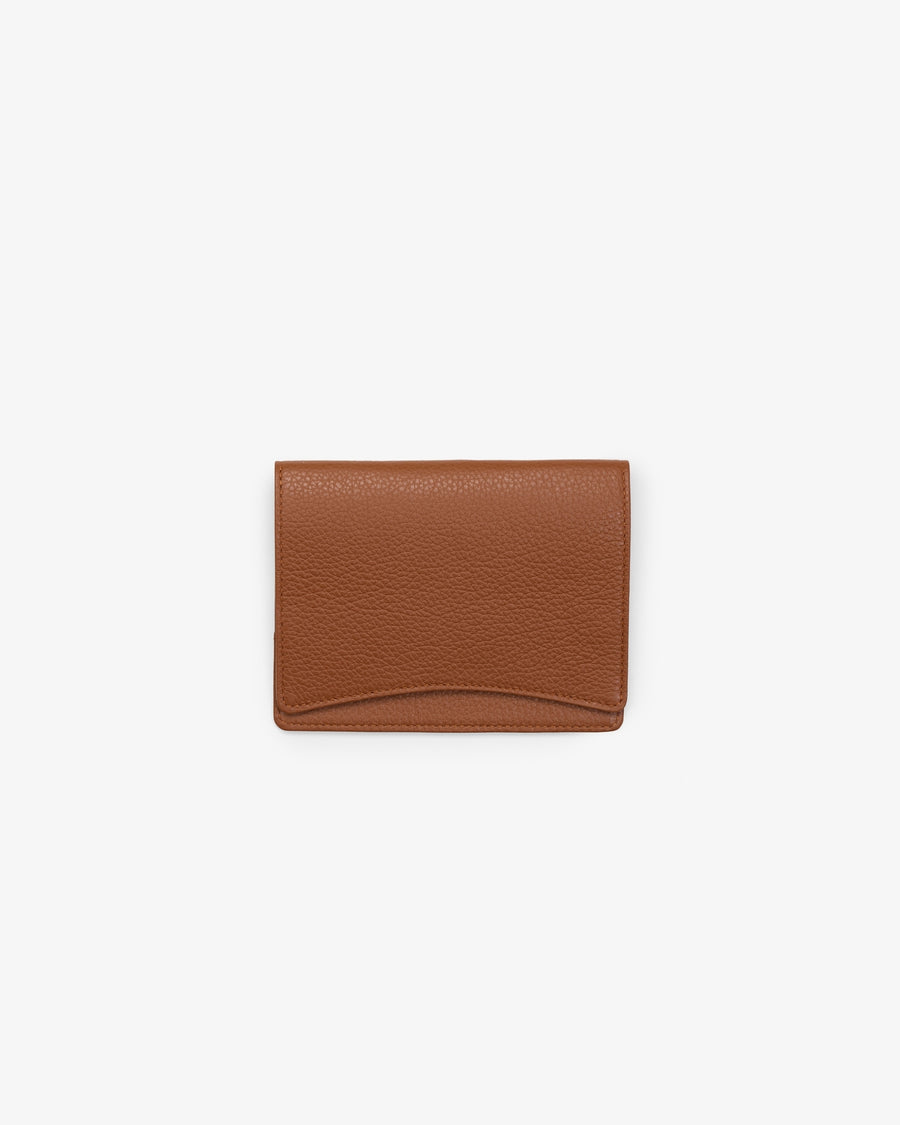 A tan leather passport holder, shown against a white background. 