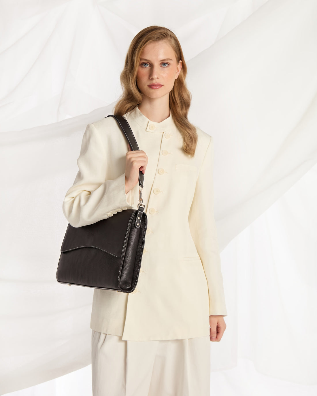 A black textured leather shoulder bag with a curved top handle, silver-tone hardware, and contrast stitching, shown against a plain white background.