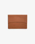 A minimalist tan leather laptop holder with a curved seam detail on the front flap, shown flat against a clean white background.