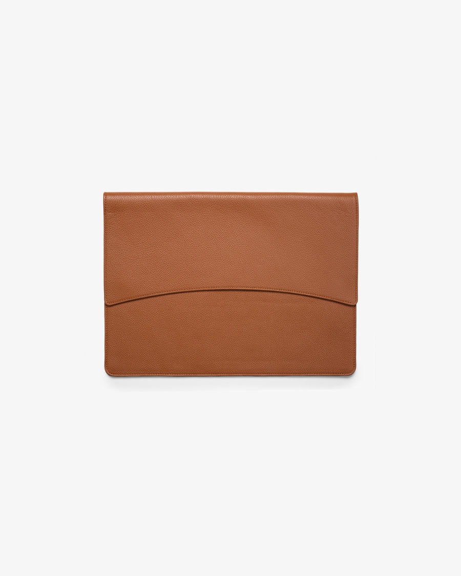 A minimalist tan leather laptop holder with a curved seam detail on the front flap, shown flat against a clean white background.