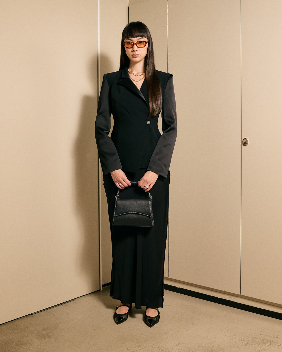 A black pebbled leather handbag with contrast stitching, silver hardware and a structured top handle, shown against a plain white background.