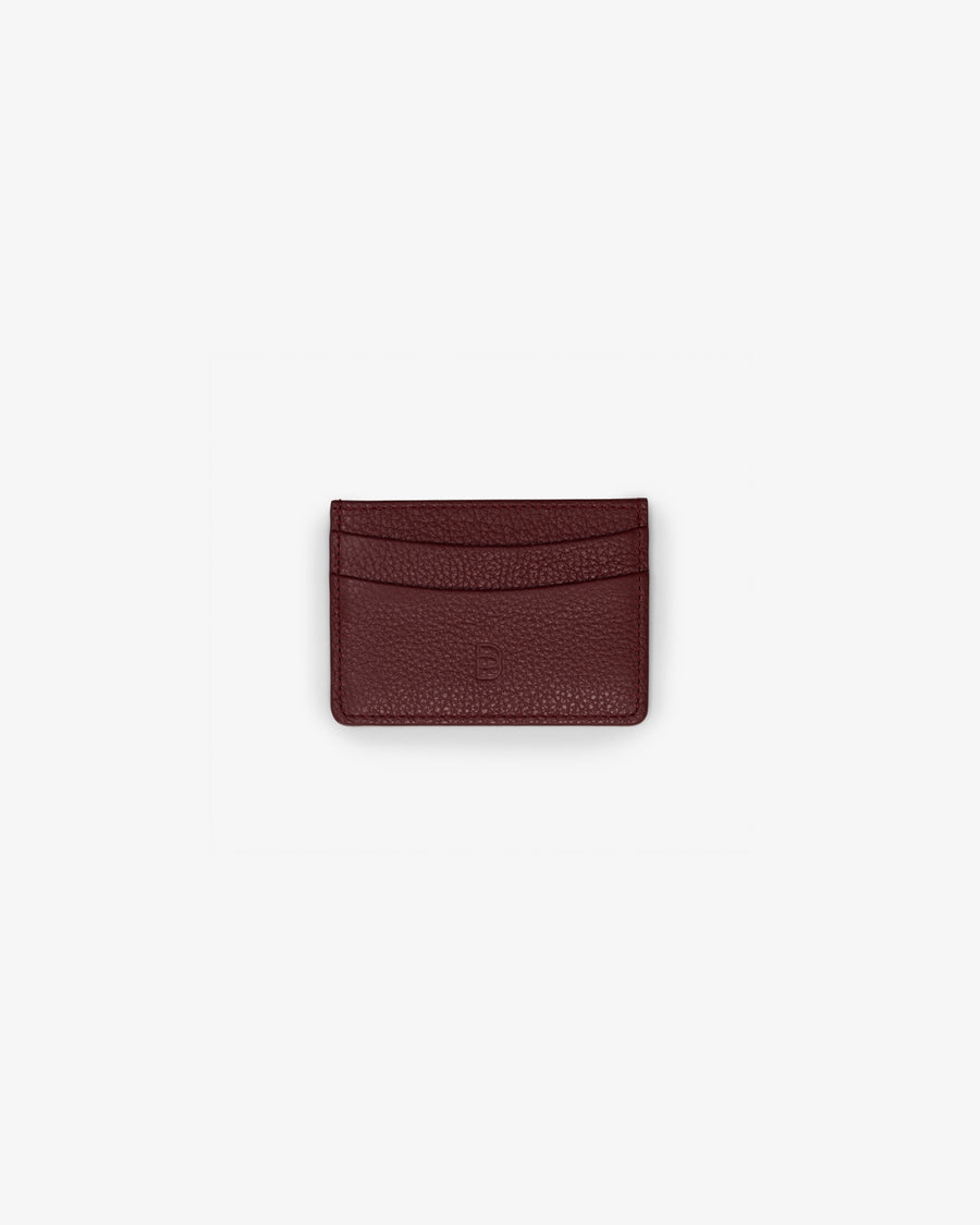 A small dark red textured leather card holder wallet centered on a light gray background.