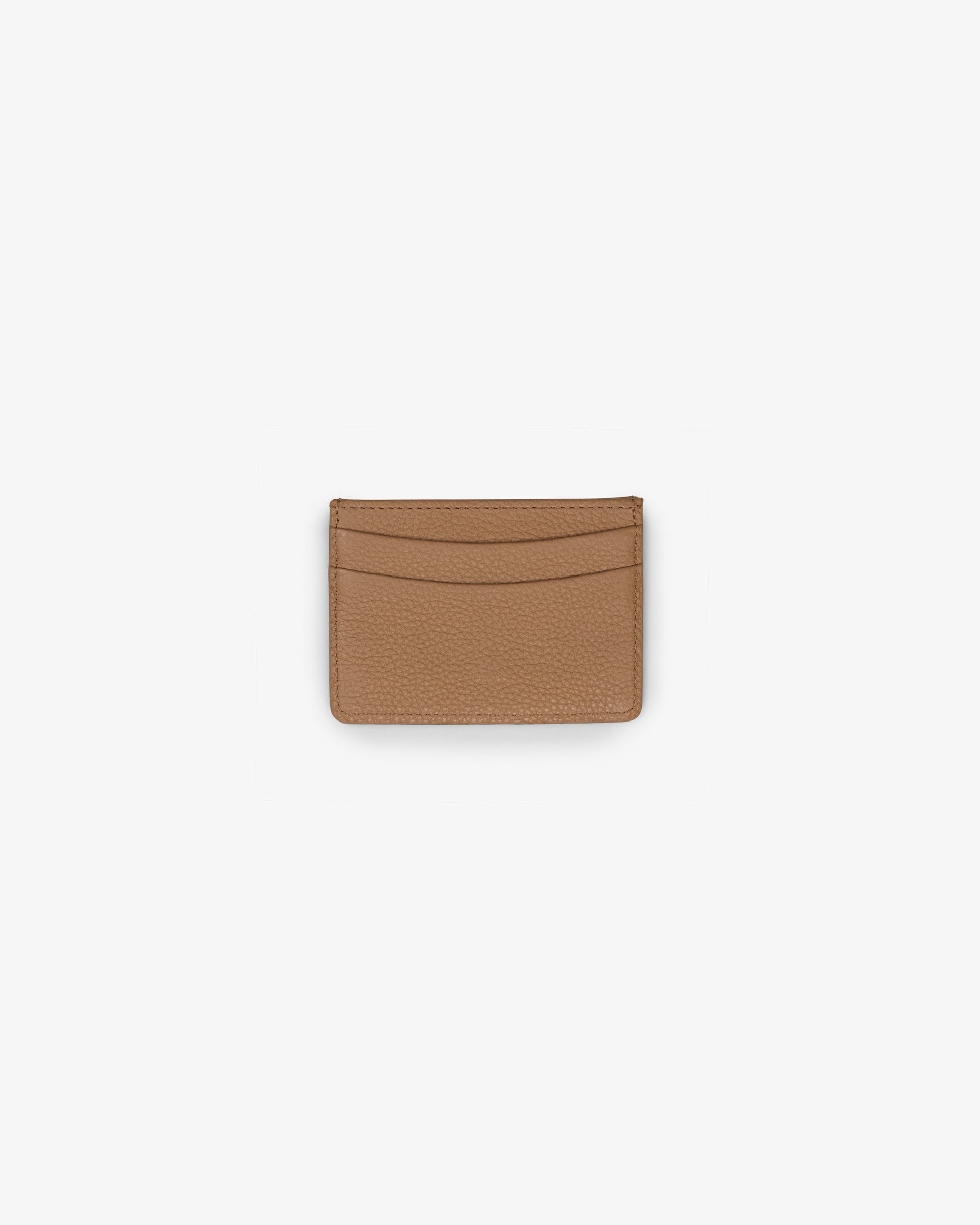 A slim, minimalist card holder or wallet made of textured tan leather, shown flat against a solid white background.