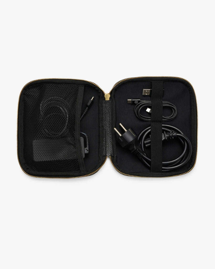 An open black zippered carrying case with gold-tone zipper trim, shown against a light gray background. Inside, black cables and accessories are organized in mesh pockets and elastic loops.
