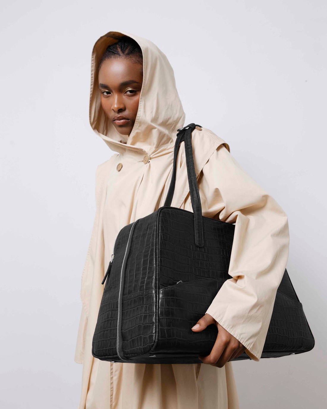 A black crocodile-embossed leather tote bag with dual top handles, shown against a plain light gray background.