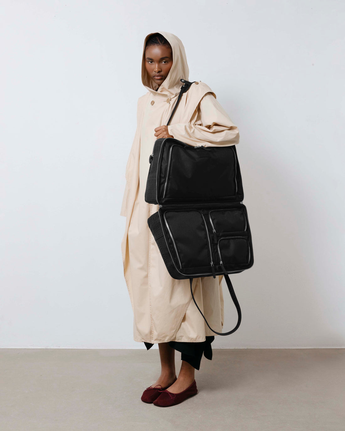 Person holding a black leather bag against a plain background