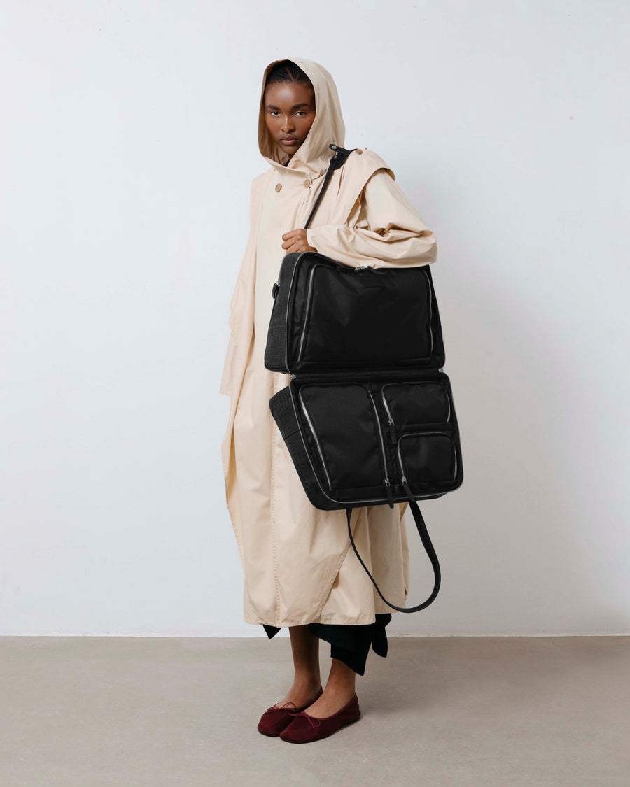Person holding a black leather bag against a plain background