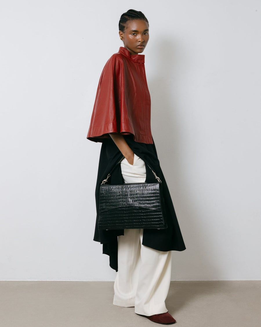 Person wearing a red cape and black bag against a white background