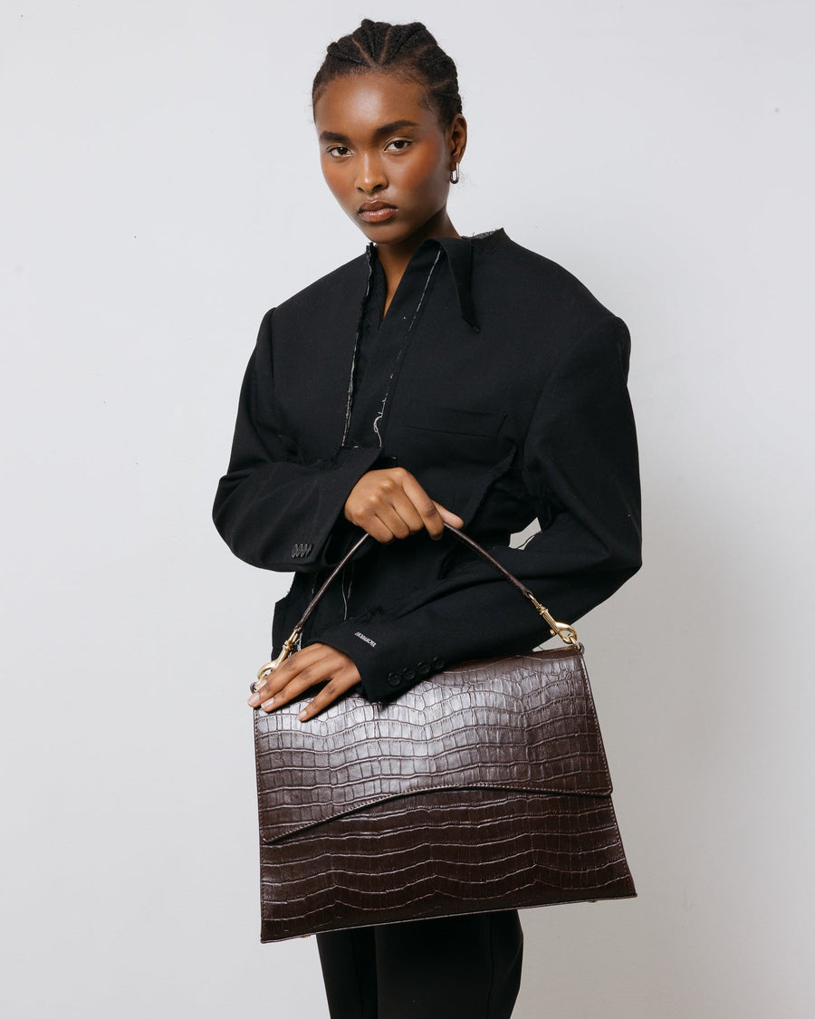 Woman holding a brown handbag against a white background