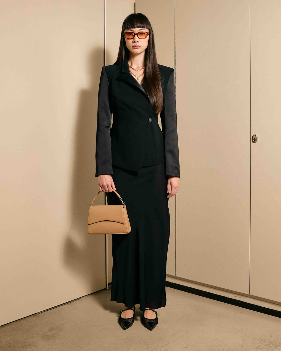 Stylish woman in black suit holding the After Work Bag in biscuit/silver – a modern handbag for professional and after-hours looks.