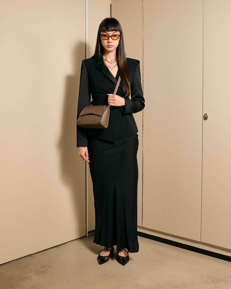 Model dressed in black wearing the After Work Bag in mocha/gold – warm-toned bag elevating any office-to-dinner look.