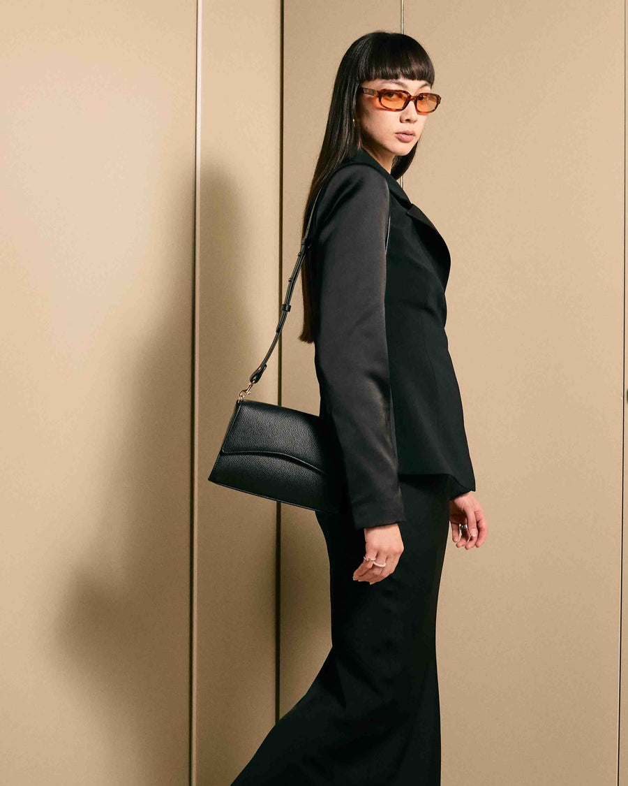 Chic black outfit paired with the After Work Bag in black/gold – timeless handbag for confident everyday wear.