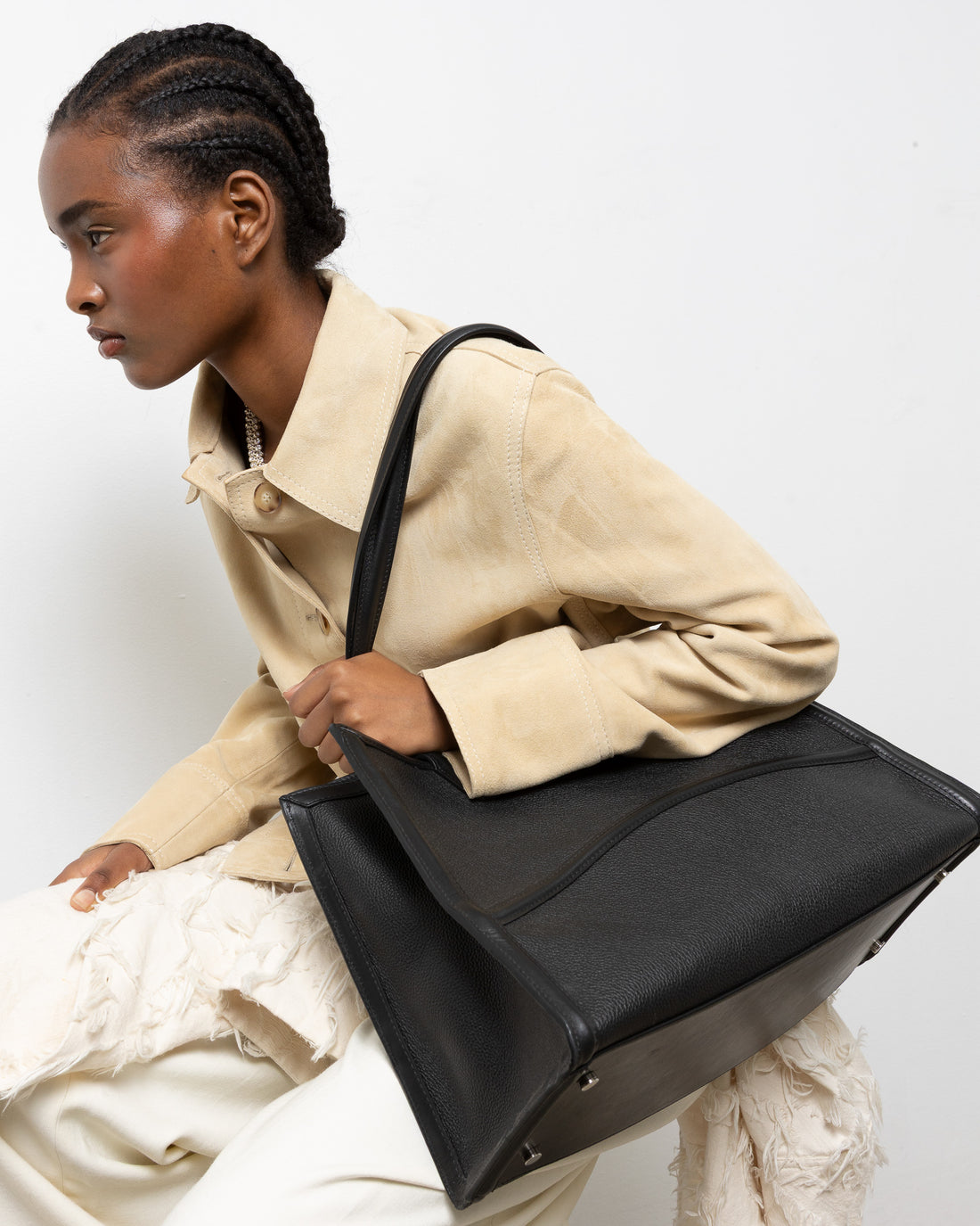 A black leather tote bag with double shoulder straps, displayed against a clean, light gray background.