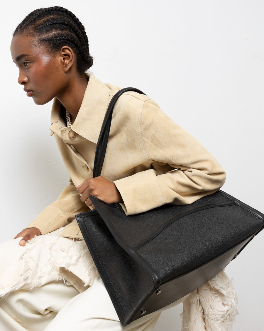 Woman holding a black leather bag against a white background