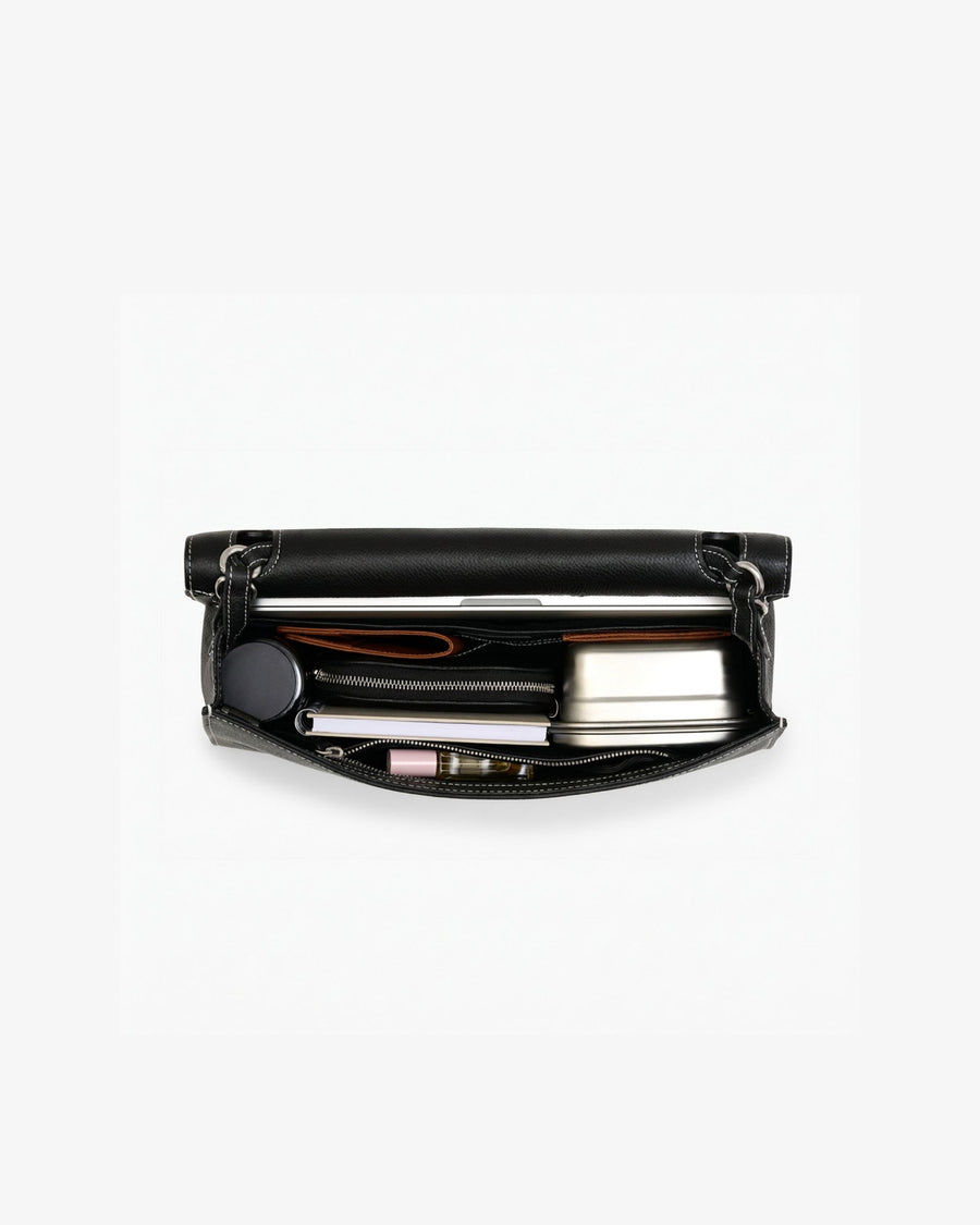 An open leather briefcase in black with white contrast stitching, showcasing items inside the bag. 