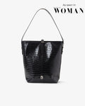A black crocodile-embossed leather shoulder bag with a single strap, shown against a light gray background with 'As seen in Emirates WOMAN' text in the upper right.