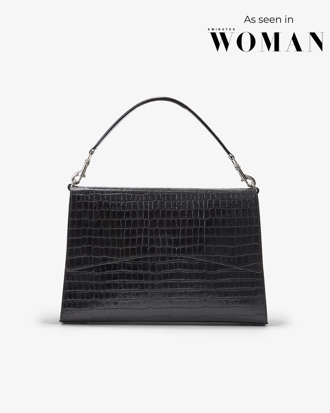A black crocodile-embossed leather handbag with a single top handle and silver-tone hardware, shown against a light gray background with 'As seen in WOMAN' text in the upper right.