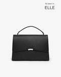 A structured black leather handbag with a top handle and a silver-tone metal accent on the front flap, shown against a light gray background with 'As seen in ELLE' text in the upper right.