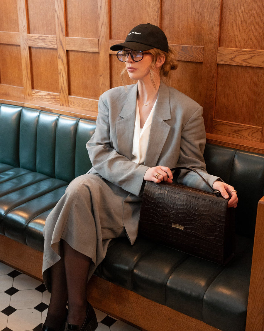 Person sitting on a black leather bench in a room with wooden paneling.