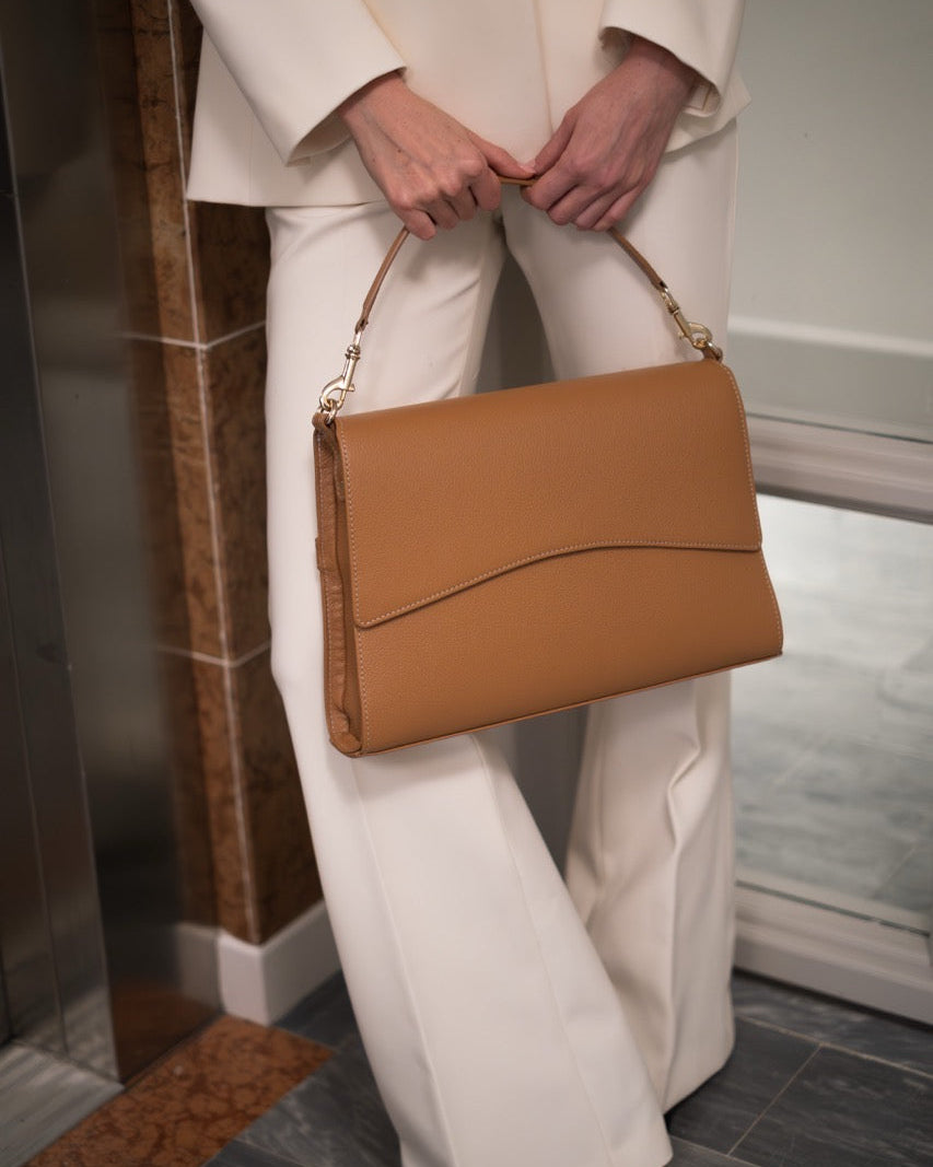 Person holding a brown handbag in an indoor setting