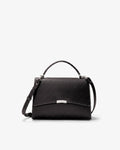 A black leather top-handle handbag with a long shoulder strap and a silver-tone metal accent on the front flap, shown against a plain white background.