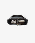 A top-down view of a black leather shoulder bag with a structured curved silhouette, featuring a central strap closure with a gold-tone buckle and a zippered pocket containing books or folders, set against a white background with thin red horizontal guideline markings.