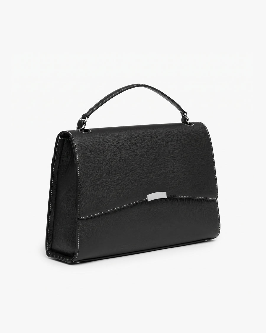 A black leather top-handle handbag with a silver-tone metal accent on the front flap and contrast stitched seams, shown from a three-quarters angle against a plain white background.