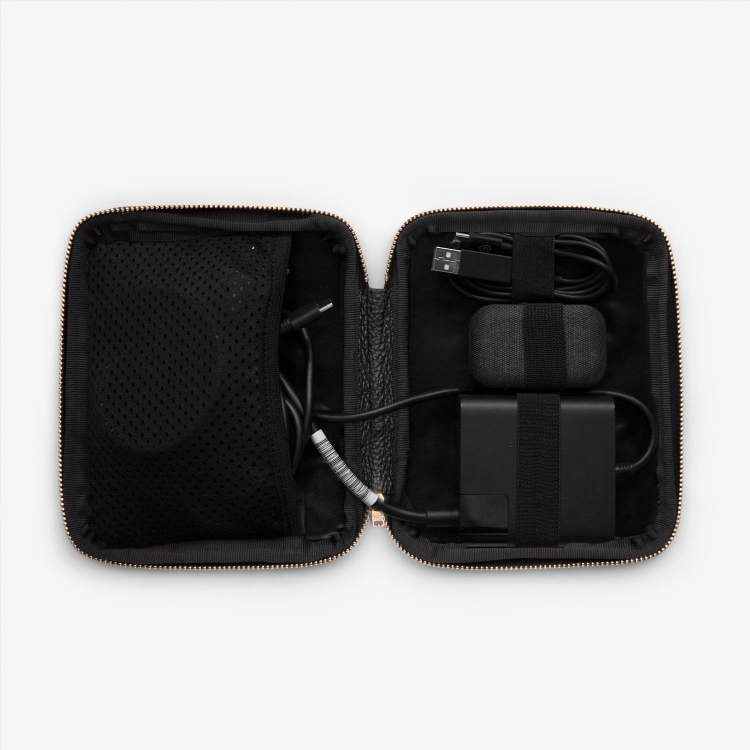 Shows the inside of a cable pocket displaying a computer charger, headphones, phone charger, and other cables, all neatly arranged and organized for easy access while on the go.