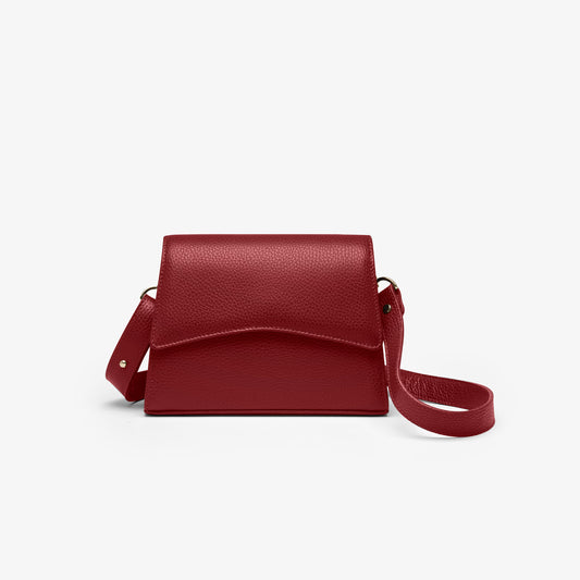 A red grained leather handbag with light gold metalware and an adjustable strap for a comfortable crossbody or shoulder fit.